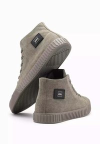 Zapatillas altas de lona verde oliva con superficie texturizada, punta redonda, suela de goma y parche con logotipo negro en el lado. Cintas y ojales reforzados.