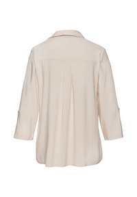 Blusa beige chiaro con maniche lunghe, dettaglio della piega dietro e colletto. Il tessuto sembra morbido e svasato con una trama liscia.