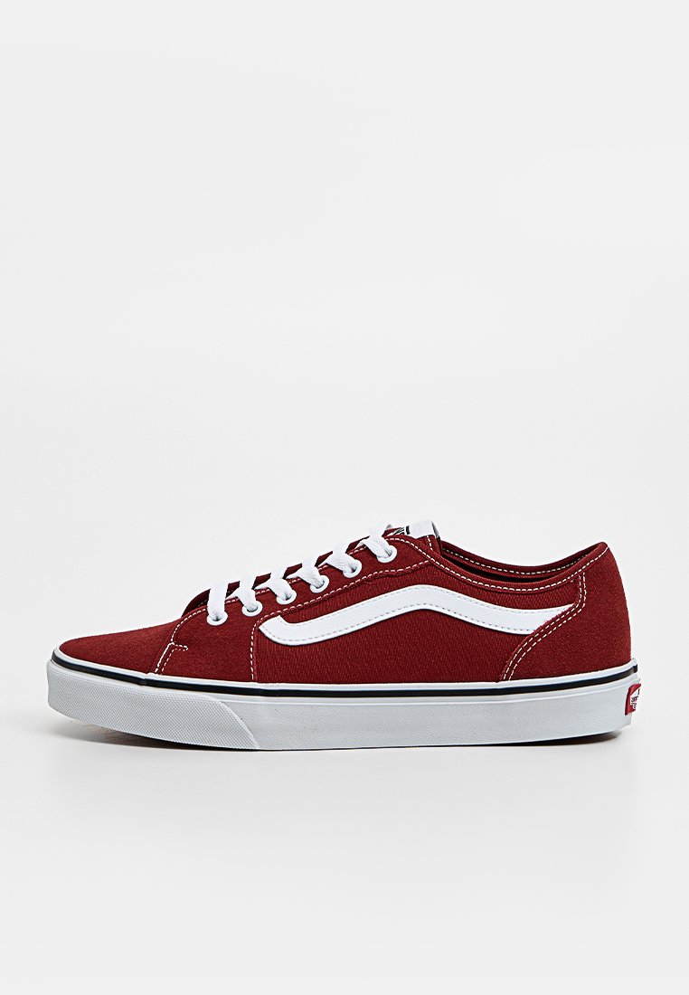 Zapatillas de lona rojas de corte bajo con cordones blancos, franja lateral blanca contrastante y suela de goma negra. Presenta un acabado de tela texturizada.