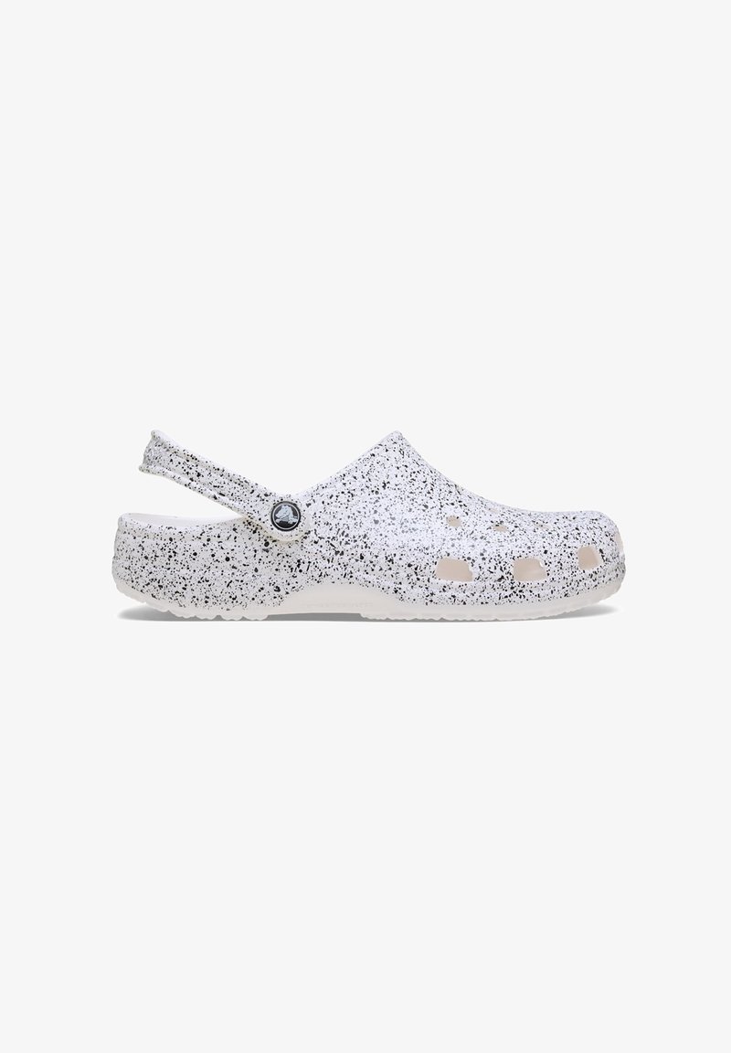 Sabot blanc et noir moucheté à enfiler avec des trous de ventilation et une bride arrière réglable, montré en profil latéral sur fond blanc.