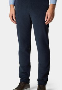 Granatowe spodnie w korduroy o fakturowanym wykończeniu, dopasowane, z bocznymi kieszeniami, w zestawie z ciemnobrązowymi trampkami i koszulą w kratę.