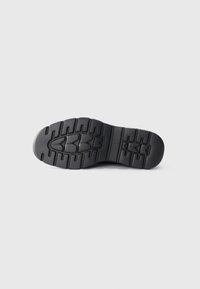 Suola di sneakers nera con un motivo di battistrada robusto, caratterizzata da gomma testurizzata per aderenza e flessibilità. Design minimalista senza decorazioni.