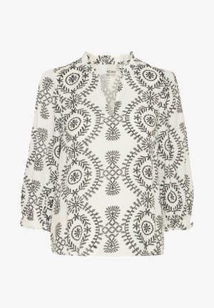 Valge pluus mustade lillede tikanditega, millel on volangkaelus, pikad varrukad ja lõdvestunud sobivus. Silmatorkavad ringikujulised mustrid üle kogu pluusi.