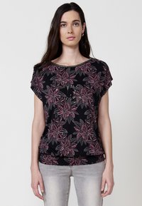 Chemise noire à motifs floraux en rose et gris, à manches courtes et avec un bas froncé. Tissu lisse avec un léger brillant.