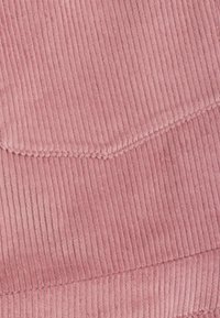 Rosa kordflors tyg, med vertikala ribbor, en jämn textur och en subtil lyster. Kanterna är sömda för hållbarhet.