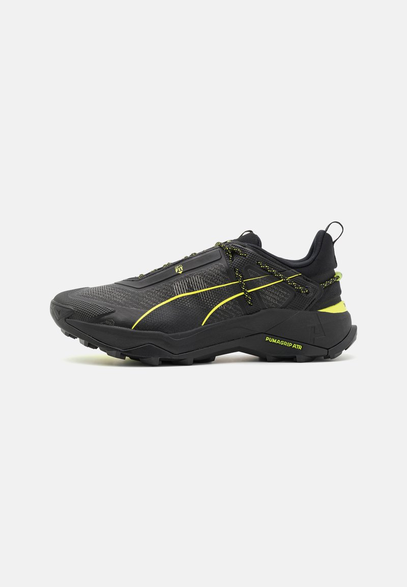 Scarpe da ginnastica nere con tessuto texturizzato, dettagli gialli e suola robusta. Presentano un sistema di allacciatura sicuro e un tallone rinforzato.