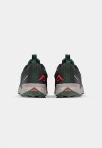 Chaussures de sport noires et vertes avec une tige texturée, une languette au talon et des accents roses sur le talon et le logo. Semelle intermédiaire mouchetée.