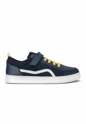 Granatowy sneaker z białą podeszwą, żółtymi sznurówkami, białym paskiem z boku i granatowym paskiem na rzep na białym tle.