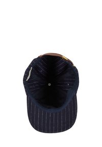 Vista interna di un cappellino da baseball blu navy a righe con una fibbia metallica e cinturino regolabile marrone su sfondo bianco.