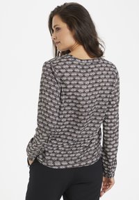 Blusa nera a maniche lunghe con un motivo a ventaglio in grigio e bianco, caratterizzata da un collo rotondo e una vestibilità rilassata. Tessuto morbido.