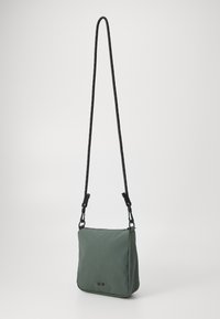 Borsa a spalla di stoffa verde con forma rettangolare, tracolla nera regolabile e due piccoli bottoni neri sul davanti. Texture liscia.