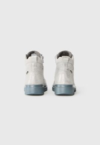 Bottines gris clair avec une finition métallisée, tige en daim texturé et semelle en caoutchouc bleu épais. Présente une fermeture éclair latérale pour un enfilage facile.