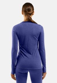 Long-sleeve top in solid purple fabric, featuring a rounded neckline and fitted design. Soft texture with smooth seams, paired with matching bottoms.