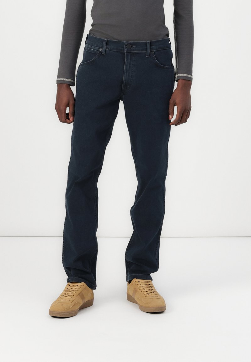 Mørkeblå jeans med rett ben, laget av denimmateriale, med fem lommer og en enkelt knappelukking.