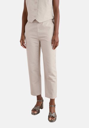 Beige linen trousers with a straight fit, side pockets, and a smooth texture, complemented by silver heeled sandals with a knot design.