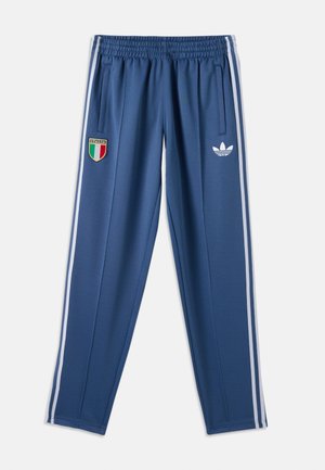 Μπλε παντελόνι φόρμας με λευκές ρίγες στο πλάι, ελαστική μέση, λογότυπο Adidas δεξιά και ταμπέλα με τη σημαία της Ιταλίας στο αριστερό μηρό.