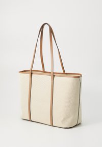 Beige canvas tote bag with brown leather handles, rectangular shape, top stitching detail, and an open top for easy access.