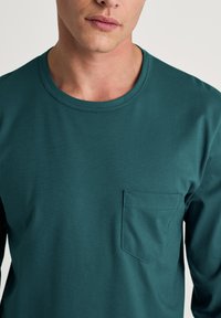 Turkoois shirt met lange mouwen gemaakt van katoen, met een ronde halslijn en een borstzak met een gestikte rand. Gladde textuur.