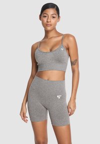 Szary zestaw sportowy składający się z krótkiego topu na cienkich ramiączkach oraz szortów z wysokim stanem, wykonany z elastycznego, strukturalnego materiału. Biały akcent z logo.
