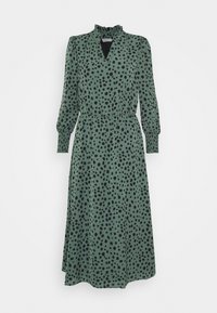 Robe midi verte à pois noirs, avec un col froncé, des manches longues et une taille cintrée pour mettre en valeur la silhouette. Tissu à texture lisse.
