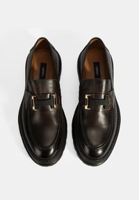 Schwarze Lederloafers mit glänzender Oberfläche, ausgestattet mit einer schwarzen und goldenen dekorativen Schnalle sowie einer strukturierten Sohle. Gefüttertes Innenleben.