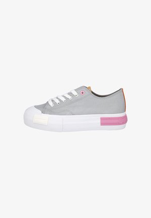 Zapatilla baja de lona gris claro con cordones blancos, suela blanca gruesa, ojal y detalle en el talón en rosa, lengüeta del talón naranja y puntera redondeada.