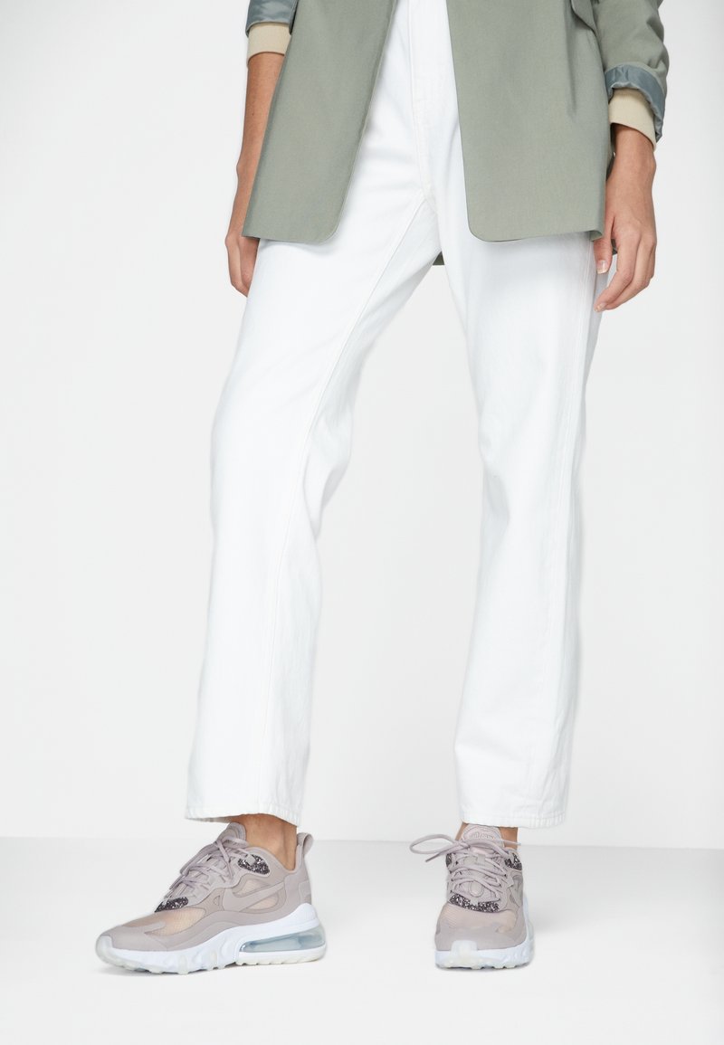 Light gray sneakers with a textured mesh upper, transparent air cushioning sole, and subtle dark accents. Worn with white, loose-fitting pants.