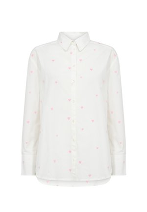 Camicia bianca con bottoni e maniche lunghe, caratterizzata da piccoli motivi a cuore rosa distribuiti uniformemente su tutta la superficie. Materiale morbido e leggermente testurizzato.