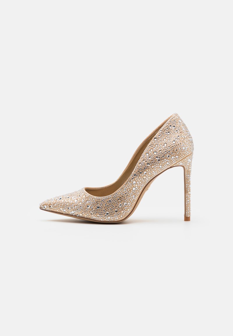 Beige színű, hegyes orrú magassarkú cipő, ezüst és átlátszó rhinestone díszítéssel. Stiletto sarokkal és sima bélésű belső résszel rendelkezik.