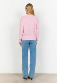 Maglione rosa chiaro con una texture morbida, scollo rotondo e maniche lunghe, abbinato a jeans a gamba larga blu chiaro.
