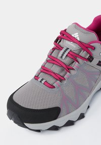 Chaussure de randonnée Columbia grise et rose avec tige en mesh, embout noir, lacets roses et semelle grise à motifs sur fond blanc.