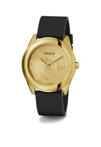 Zlatni sat s teksturiranim zlatnim brojčanikom koji ima uzorak, odnosno crnim gumiranim remenom. Na brojčaniku se nalazi logo marke "GUESS".
