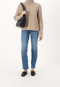 Beige ribbed turtleneck-paita, siniset suorat farkut, mustat saapasmalliset kengät ja musta olkalaukku. Tekstuurit kontrastoivat sileän nahan kanssa.