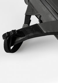 Grau gefärbter Stoffbeutelriemen mit schwarzen Nylonelementen und Kunststoffschnalle; verfügt über Nähte und Logodetails am Riemen.