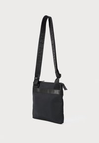 Black rectangular crossbody bag with adjustable shoulder strap featuring embossed "Armani Exchange" text and zipper closure on top.