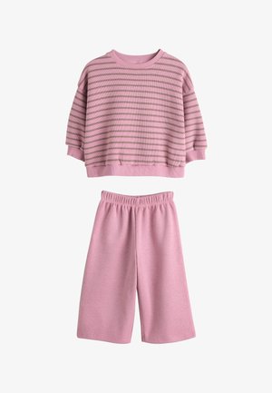 To-delt sæt med en løs, langærmet top med pink og brune striber og ensfarvede, brede pink shorts med elastik i taljen.