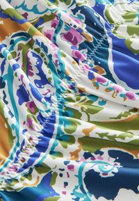 Multikleurige stoffen met blauwe, groene, roze en gouden bloemmotieven met een geplooide textuur; gladde afwerking.