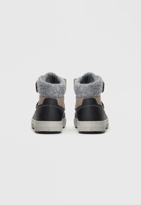 Baskets montantes combinant du cuir noir et du feutre gris clair. Présente une semelle texturée et un col intérieur en gris doux.