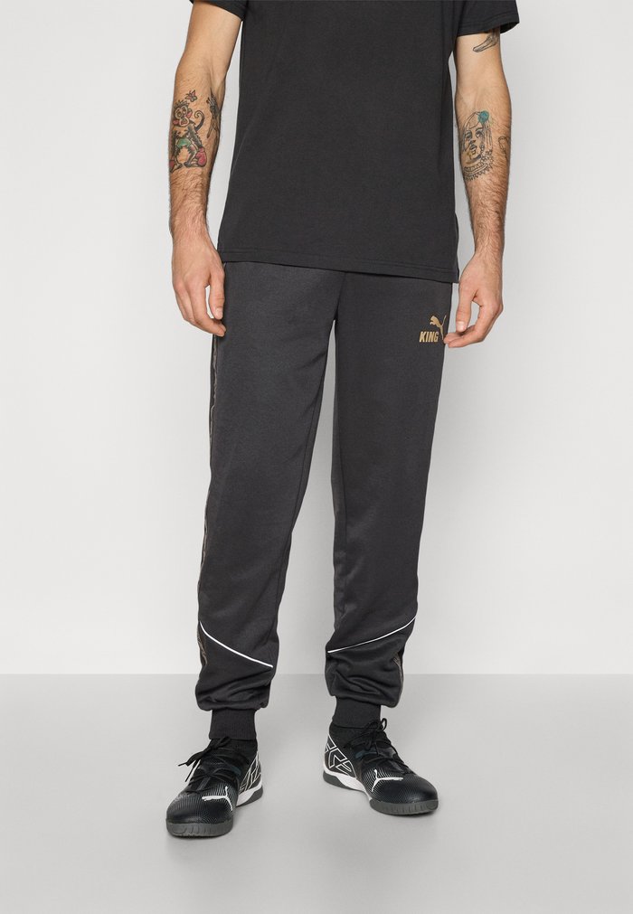 PUMA Tracksuit bottoms - black/matte gold-coloured/white