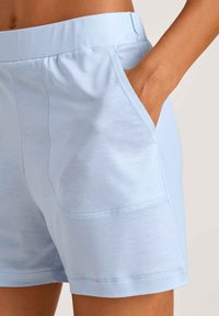 Lichtblauwe sportshorts met een zachte textuur. Voorzien van een elastische tailleband, zijzakken en contrasterende stiksels langs de zomen.