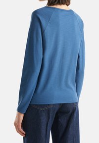 Långärmad blå skjorta i ett mjukt tyg med avslappnad passform, med raglanärmar och rundad halsringning.