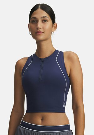 Navy blue athletic crop top with a half zip, sleeveless design, perforated texture for breathability, and white accent stitching.