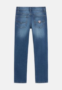 Jean en denim bleu foncé, coupe droite, finition délavée, deux poches arrière avec couture contrastante et un petit patch logo sur la poche droite.