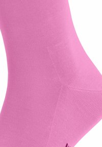 Calzino rosa, elasticizzato, con una superficie liscia e lavorata a maglia. Il design presenta un bordo a costine e una costruzione senza cuciture per garantire comfort.