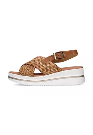 Sandal in paglia intrecciata e pelle marrone con cinturini incrociati, fibbia alla caviglia regolabile e suola piatta bianca con un sottile accento beige.