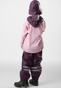 Waterproof rain jacket in pink with a purple hood. Matching purple pants with reflective stripes. Rubber boots complete the outfit.