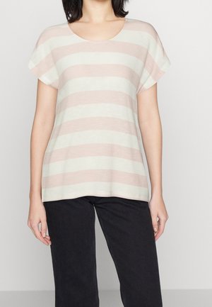 Vrouw draagt een kortemouw roze-wit met brede horizontale strepen top gecombineerd met een zwarte broek tegen een effen lichte achtergrond.