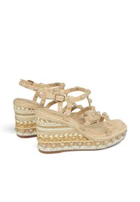 Sandales compensées beiges avec plusieurs lanières croisées, fabriquées en daim, dotées d'une semelle espadrille tissée avec des accents blancs, beiges et jaunes.
