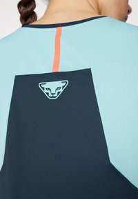 Gaismas zila un tumši zila īsu piedurkņu sporta krekls ar teksturētu audumu. Ar kontrastējošu oranžu svītru un logotipu uz muguras.
