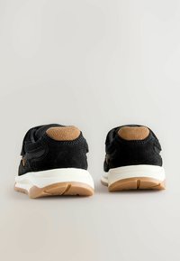 Czarne sneakersy z zamszowymi akcentami, biała podeszwa środkowa i gumowa podeszwa zewnętrzna. Posiadają przeszycia oraz wyściółkę wokół kostki dla komfortu.